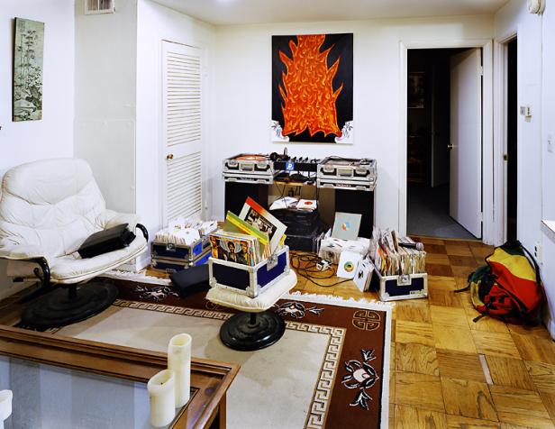 Ein Wohnzimmer mit DJ-Equipment, Schallplatten und einem Sessel.