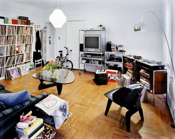 Ein Wohnzimmer mit Schallplattensammlung, Fernseher, Fahrrad und verschiedenen Möbeln.