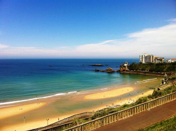 Ein sonniger Strand mit türkisfarbenem Wasser und einigen Badegästen.