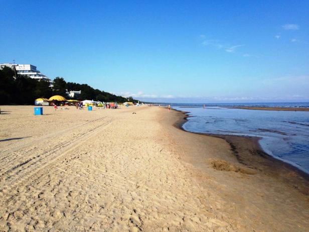 Ein Sandstrand mit ein paar Menschen und blauem Himmel.