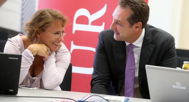 Eine Frau und ein Mann sitzen an einem Tisch und unterhalten sich lächelnd.