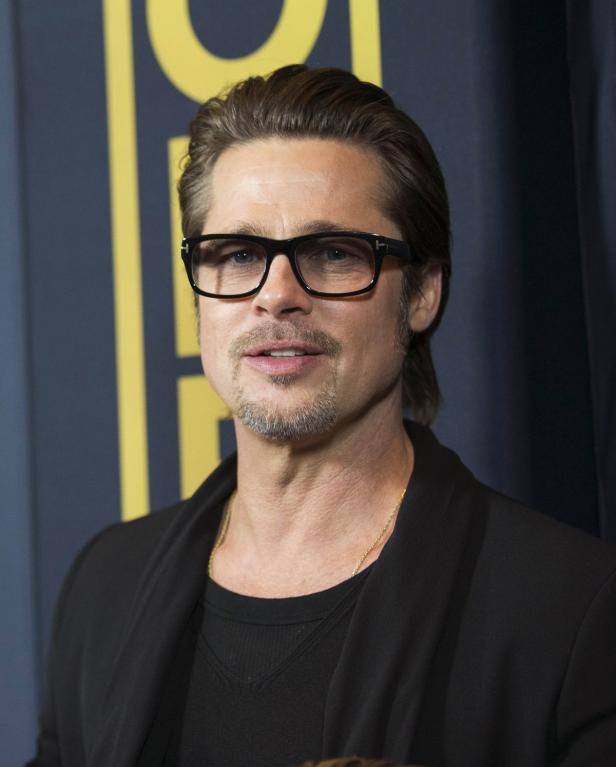 Actor Pitt poses at the premiere of "Unbroken" at Brad Pitt mit Brille und Bart vor einem dunklen Hintergrund.