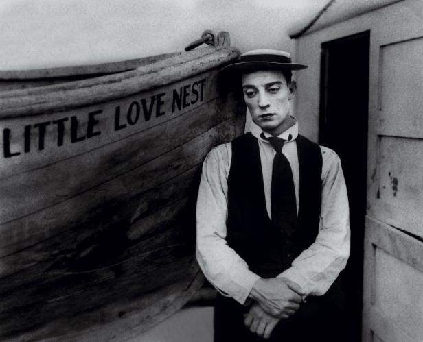 Buster Keaton steht neben einem Boot mit der Aufschrift „Little Love Nest“.