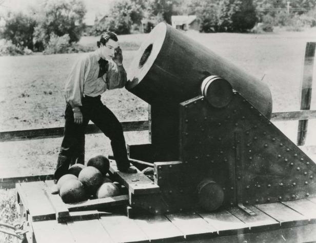 Ein Mann steht neben einer großen Kanone und blickt in den Lauf.