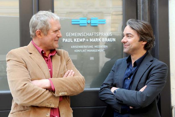 Paul Kemp und Mark Braun, die Gründer einer Gemeinschaftspraxis für Krisenberatung, stehen vor ihrer Praxis.