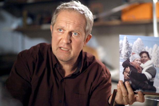 Ein Mann hält ein Foto von zwei Frauen im Schnee in der Hand.