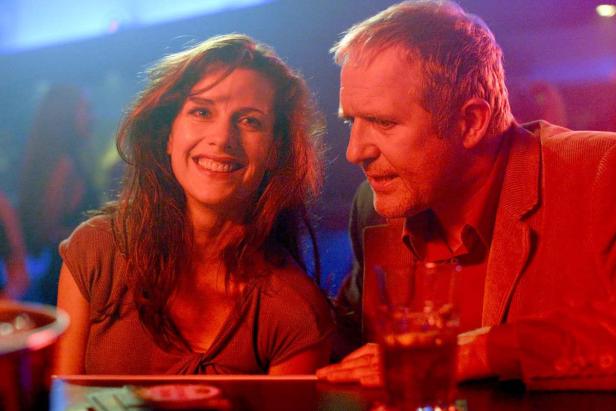 Eine Frau lächelt neben einem Mann in einer Bar.