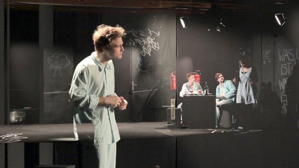Eine Theaterszene mit Schauspielern auf einer dunklen Bühne.