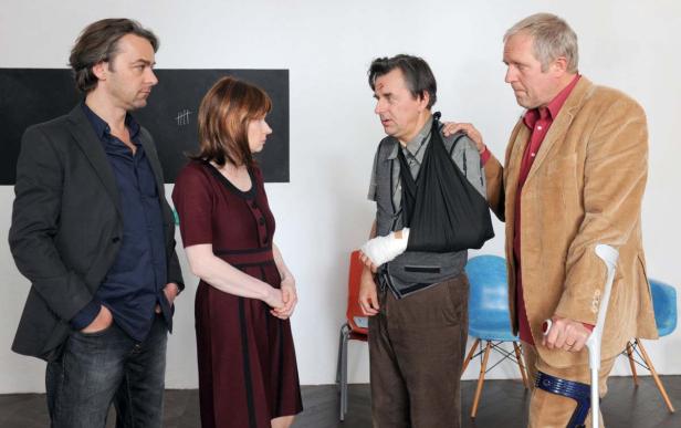 Eine Gruppe von vier Personen, von denen eine einen Arm in einer Schlinge und eine weitere eine Krücke hat.