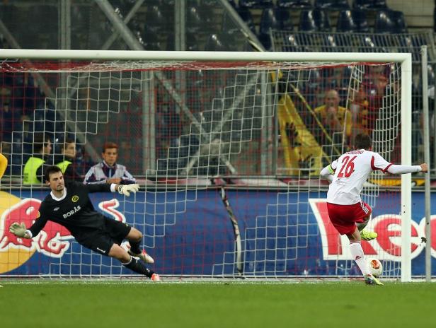 Ein Fußballspieler schießt einen Ball auf das Tor, während der Torwart versucht, ihn abzuwehren.