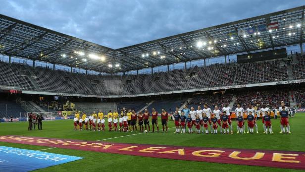 Fußballspieler und Kinder stehen vor einem UEFA Europa League Banner im Stadion.