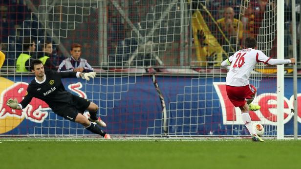 Ein Fußballspieler schießt einen Elfmeter, während der Torwart versucht, den Ball zu halten.