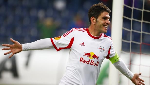 Ein Fußballspieler von Red Bull jubelt mit ausgestreckten Armen auf dem Spielfeld.