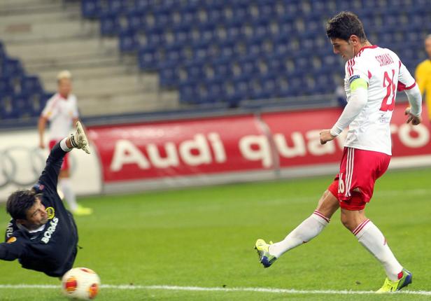 Ein Fußballspieler schießt den Ball, während der Torwart versucht, ihn abzuwehren.