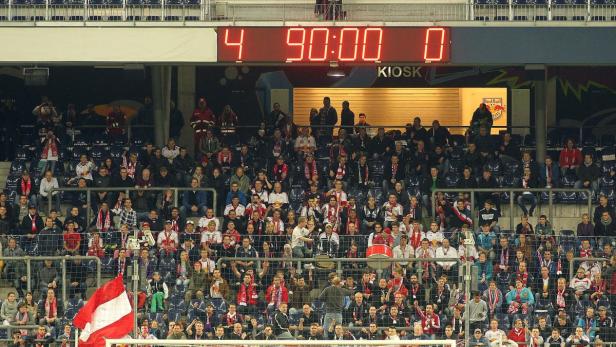 Fußballfans im Stadion jubeln beim Spielstand von 4:0 in der 90. Minute.