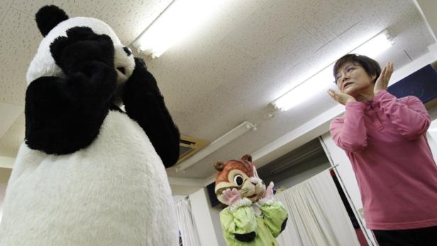 Eine Frau steht neben einem Panda- und einem Eichhörnchenkostüm.