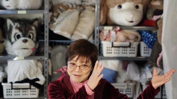 Eine Frau steht vor einem Regal voller Tierkostümköpfe.
