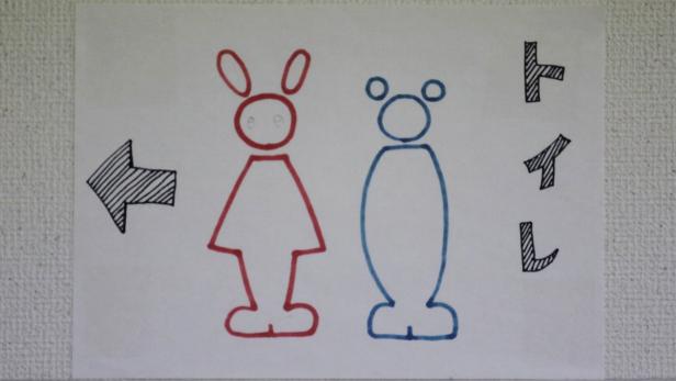 Eine handgezeichnete Toilettenbeschilderung mit stilisierten Figuren und japanischer Schrift.