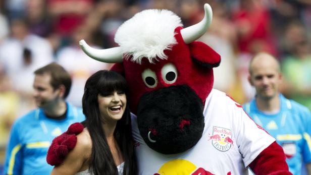 Eine lachende Frau posiert mit dem Maskottchen von Red Bull Salzburg.