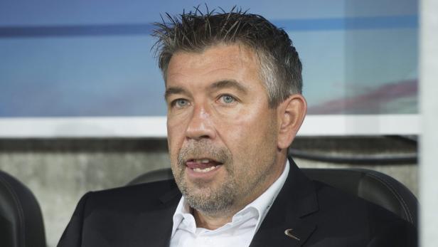 Ein Mann im Anzug mit grau meliertem Haar und Bart schaut zur Seite.