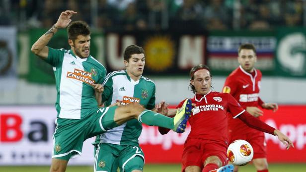 Fußballspieler in Grün und Rot kämpfen um den Ball.