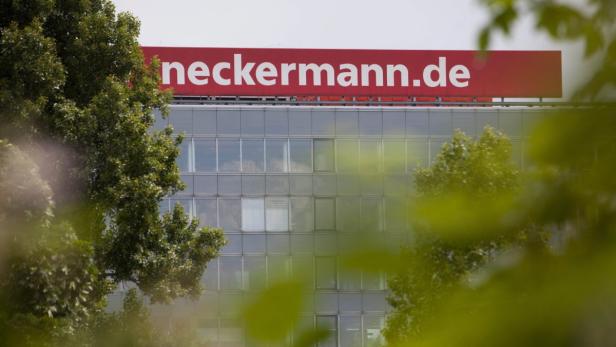 Das Neckermann.de-Logo auf einem modernen Bürogebäude, teilweise von Bäumen verdeckt.