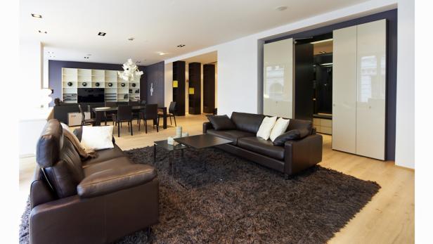 Ein modernes Wohnzimmer mit braunen Ledersofas und einem dunklen Teppich.