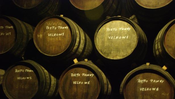 Mehrere Fässer Porto Tawny Velho lagern in einem dunklen Keller.