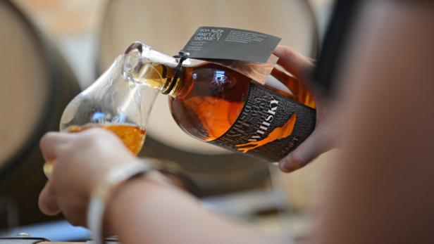 Eine Person gießt Whisky der Marke Senft in ein Glas.