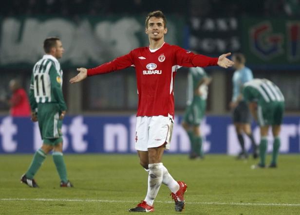 Ein Fußballspieler in rotem Trikot jubelt auf dem Spielfeld.