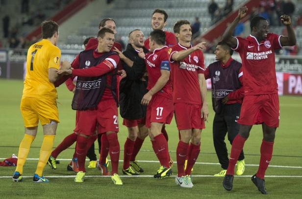 Eine Gruppe von Fußballspielern in roten Trikots feiert auf dem Spielfeld.