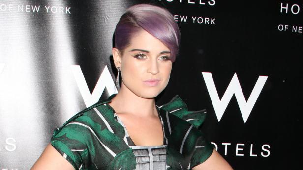 Kelly Osbourne posiert vor dem Logo eines W Hotels.