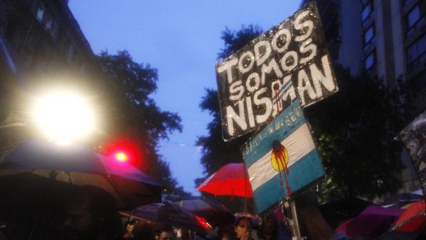 Demonstranten halten Schilder mit der Aufschrift „Todos Somos Nisman“ und eine argentinische Flagge mit Blut.