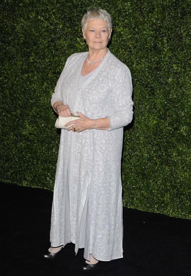 Judi Dench in einem langen, hellen Kleid mit passendem Mantel und einer Clutch.