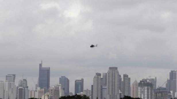 Ein Hubschrauber fliegt vor einer Skyline mit vielen Hochhäusern.