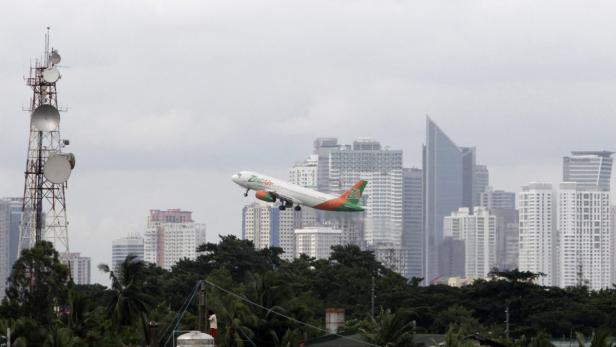Ein Flugzeug von Zest Air startet vor der Skyline einer Stadt.