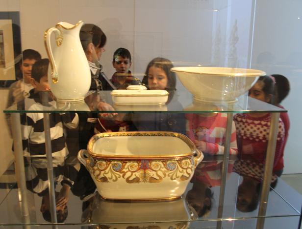 Kinder betrachten in einem Museum eine Vitrine mit Porzellanobjekten.