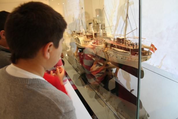 Ein Junge betrachtet ein Schiffsmodell in einer Vitrine.