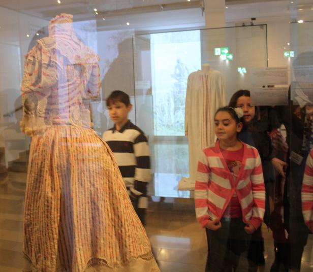 Kinder betrachten ein historisches Kleidungsstück in einer Vitrine.