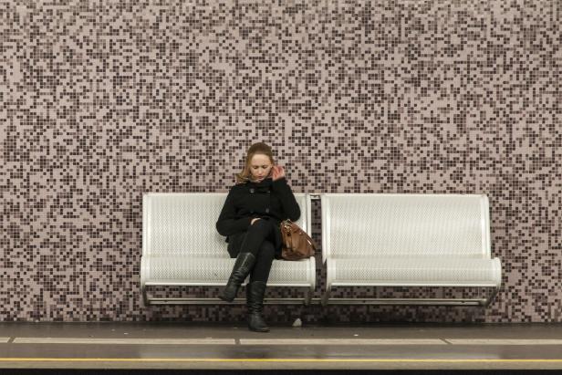 Eine Frau sitzt auf einer Bank an einer U-Bahn-Station.