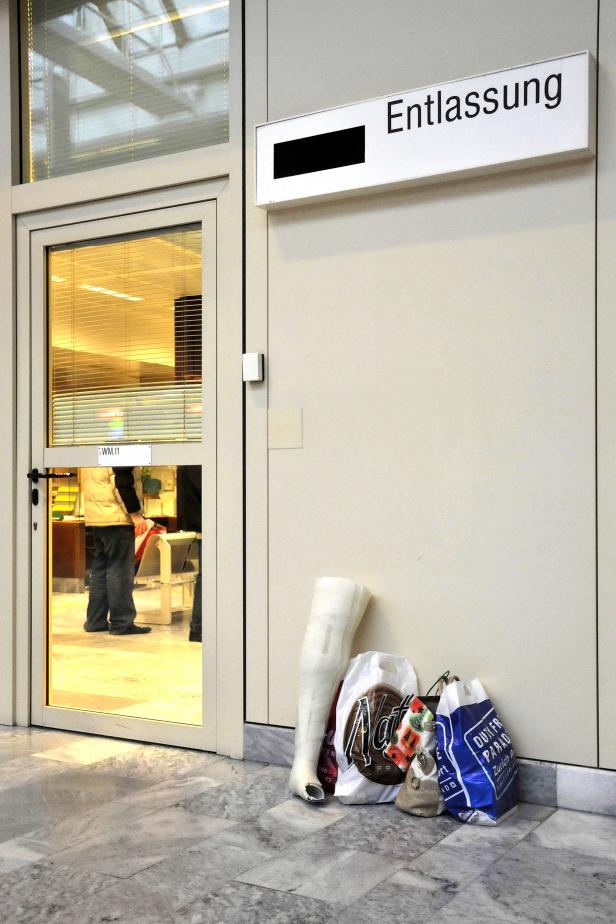 Vor einem Ausgang mit der Aufschrift „Entlassung“ stehen Einkaufstüten.