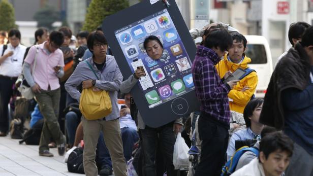 Eine Menschenmenge steht an, eine Person trägt ein übergroßes iPhone-Kostüm.