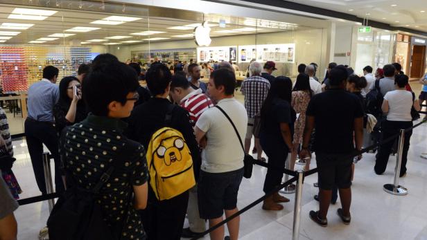 Eine lange Schlange von Menschen wartet vor einem Apple Store.