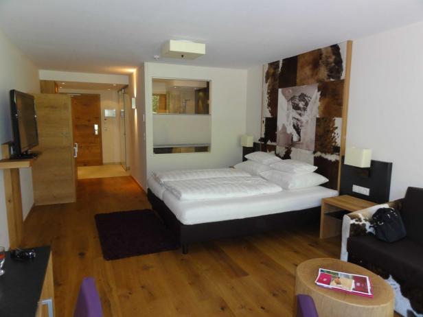 Ein Hotelzimmer mit Doppelbett, Sofa und Holzboden.