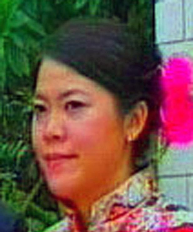 Eine Frau mit dunklen Haaren und einem rosa Haarschmuck lächelt.