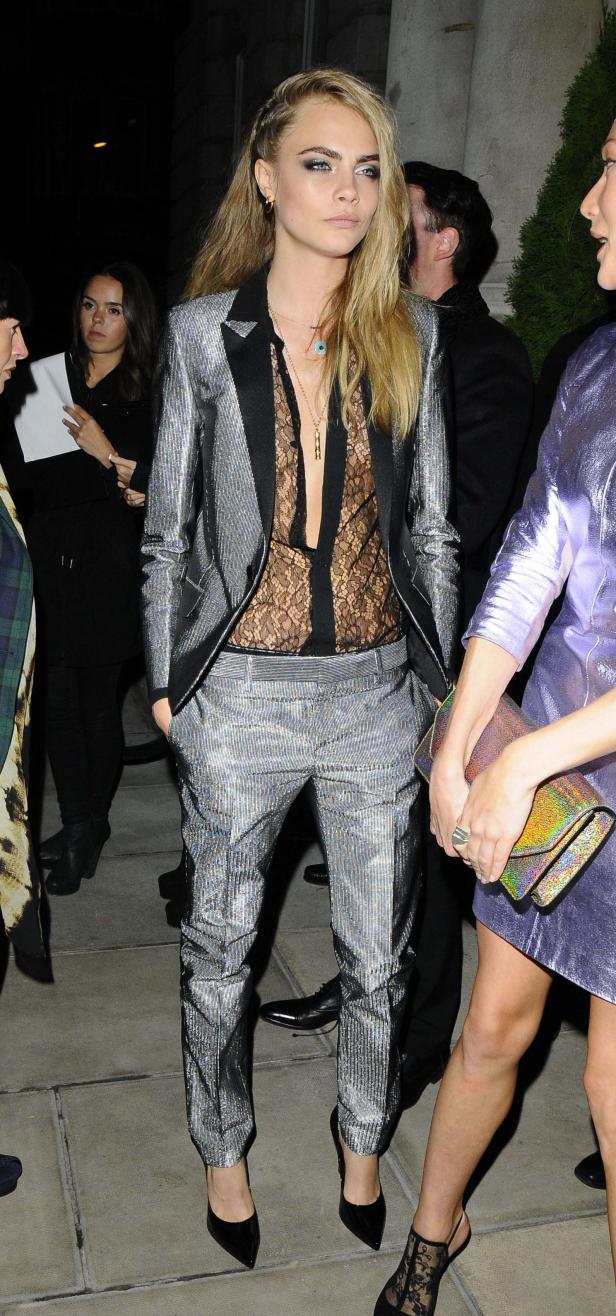Cara Delevingne trägt einen silbernen Hosenanzug mit schwarzer Spitze.