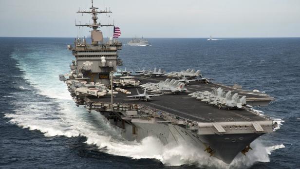 Der Flugzeugträger USS Enterprise (CVN-65) auf dem Meer mit Flugzeugen an Deck.