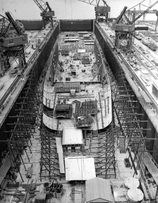 Ein Schiff befindet sich im Trockendock, umgeben von Gerüsten und Kränen.