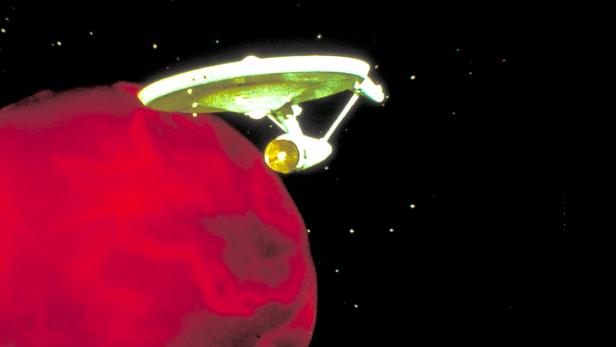 Das Raumschiff Enterprise fliegt an einem roten Planeten vorbei.