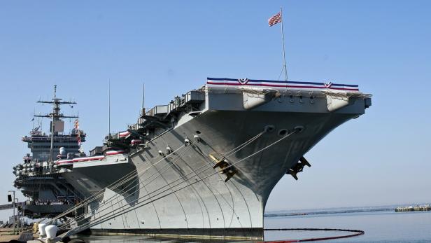 Ein Flugzeugträger mit amerikanischer Flagge liegt im Hafen.